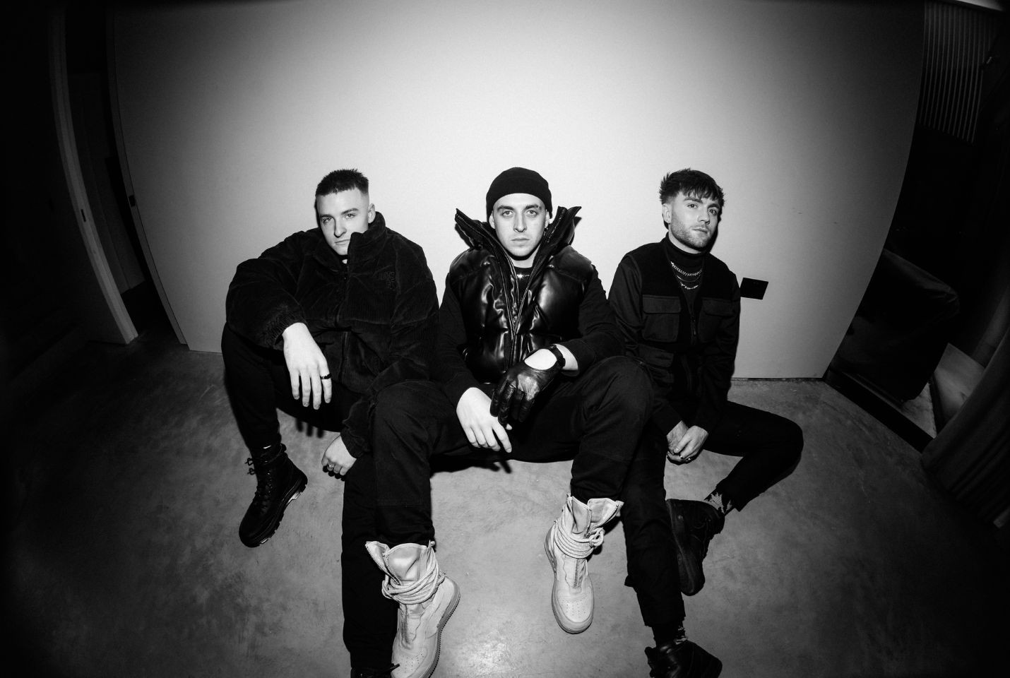 Black & White image of three men sat on the ground